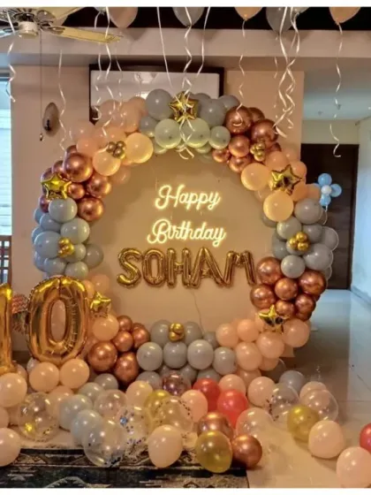 An elegant 10th birthday setup with a circular balloon arch in pastel blue and rose gold, a neon sign, and large marquee numbers.