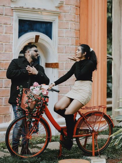 A fun and romantic pose with a flower-adorned red bicycle, capturing a sweet, vintage-inspired moment.