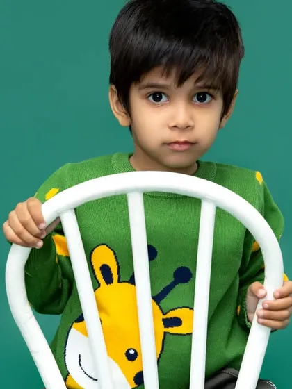 A striking and simple portrait against a solid green backdrop. Sometimes, a direct gaze and a simple setting are all that's needed to capture a child's powerful presence.