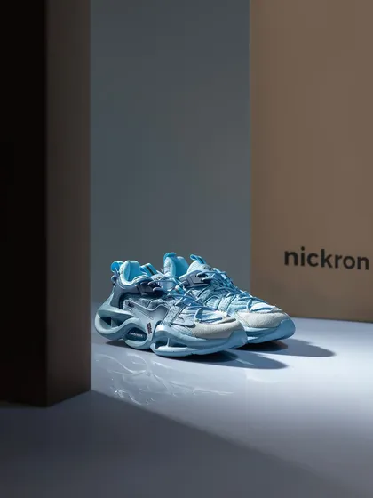 A moody, atmospheric shot of light blue sneakers. The play of light and shadow, with the branded box in the background, creates a sense of intrigue and high-end style.