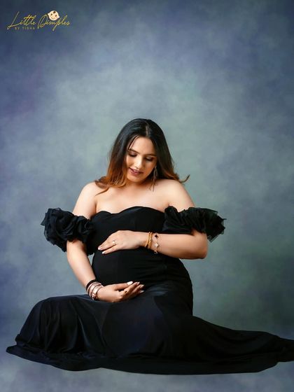 A quiet moment of connection with her baby bump. This seated pose in a classic black gown is both elegant and intimate.