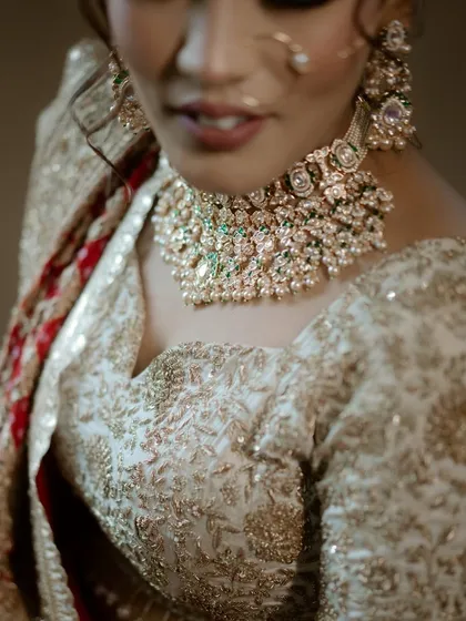 A detailed shot of the bride's jewellery and the intricate embroidery on her blouse.