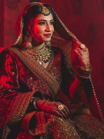 My bride Akansha, looking so regal in this red-lit portrait. The velvet outfit adds to the royal vibe.