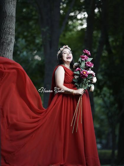 A moment of pure joy in nature. This outdoor portrait captures a candid laugh, showing the happiness that pregnancy brings, complemented by a beautiful red gown.