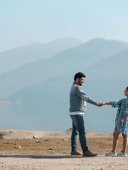 A sweet, hand-in-hand pose against a mountain backdrop, with an unexpected guest. It’s a charming and authentic slice of life in the hills.