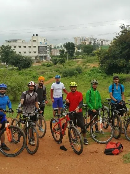 The group ready to set off from a dirt path, with a mix of urban and natural scenery in the background.