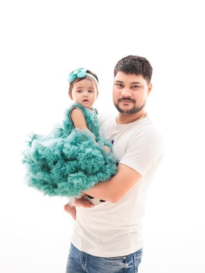 A father holding his daughter, both dressed in elegant formalwear. This creates a sophisticated and timeless portrait.