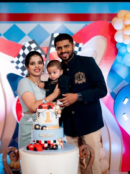 A sweet family portrait from Lakhit's "Fast One" racing party, posing with the themed cake.