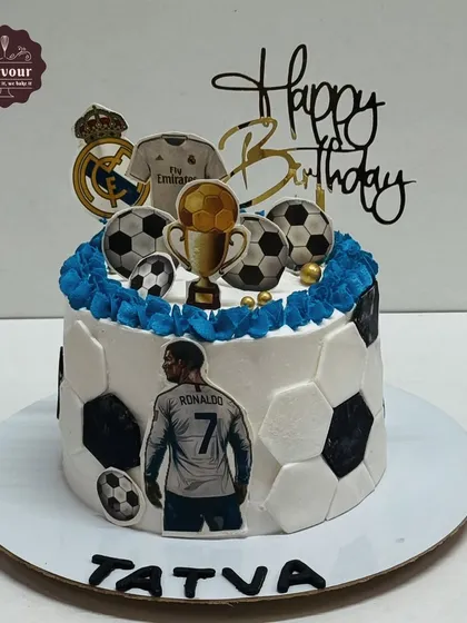 A football theme cake featuring Cristiano Ronaldo. This cake is decorated to look like a football and includes the Real Madrid logo and other themed toppers.