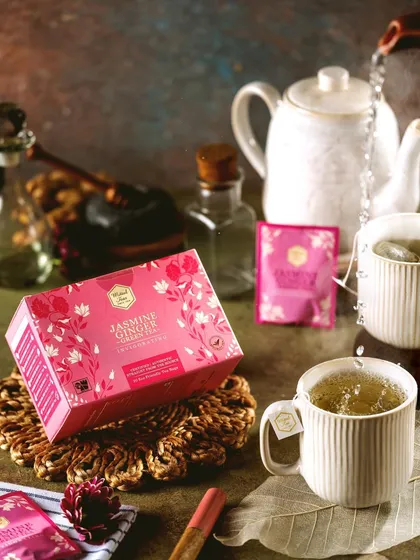 An action shot of hot water being poured over a Jasmine Ginger tea bag from Mittal Teas. The levitating box adds a creative touch, while the focus on the pour creates a dynamic and engaging image.