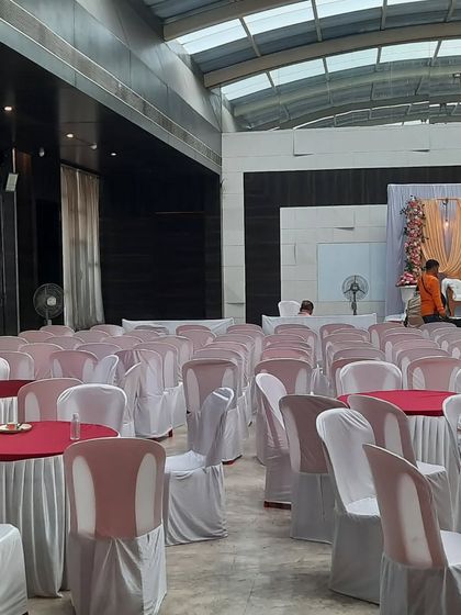 Another view of the seating arrangement in the hall, with round tables and chairs with covers, ready for the guests.