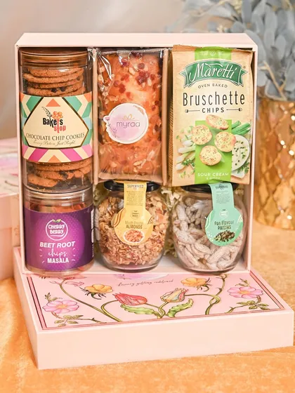 This hamper is for the sibling with a sweet tooth. It's packed with chocolate chip cookies, bruschetta chips, a delicious cake, and a variety of flavored nuts and snacks in a floral box.
