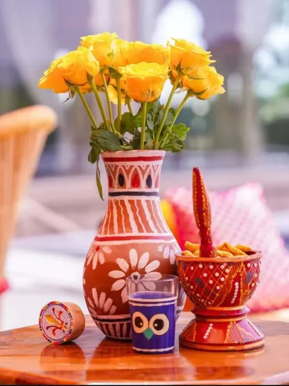 A beautiful hand-painted terracotta vase with yellow roses, adding a traditional and artistic touch to the decor.