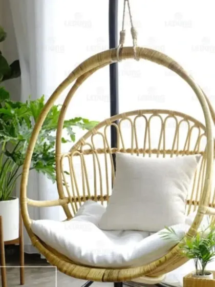 Our popular rattan hanging swing chair, shown here in a bright, plant-filled room. This piece serves as a fun and relaxing focal point, perfect for adding a playful and stylish element to your decor.