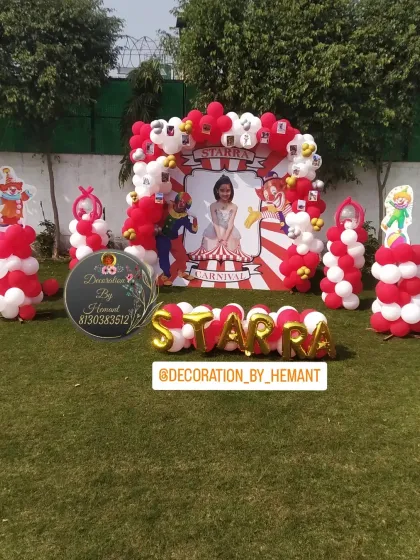 A full-scale carnival theme birthday party set up on a lawn. This shows the main photo backdrop with a personalized carnival banner, clown cutouts, and balloon columns, creating a fun and festive atmosphere for an outdoor event.