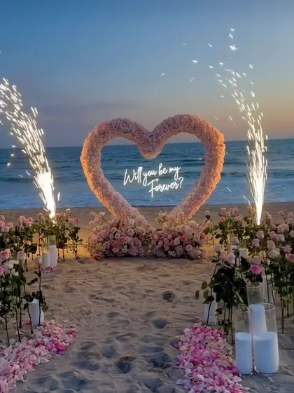 This is what a promise of forever looks like. I designed this dreamy beachside proposal with a custom floral heart arch, a neon sign, and perfectly timed pyrotechnics to create a truly unforgettable moment against the sunset.