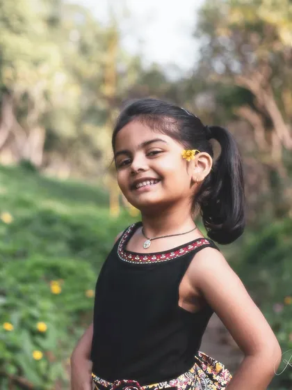 A flower in her hair and a sweet smile. This photo captures a simple, beautiful moment of a girl enjoying a day in the park, feeling connected to nature.