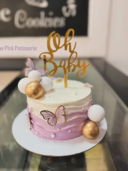 A purple ombre "Oh Baby" cake decorated with butterflies and spheres, perfect for a baby shower.