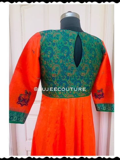 The back of the orange and green Anarkali gown. It features a simple keyhole cutout, allowing the rich green brocade fabric to be the main focus.