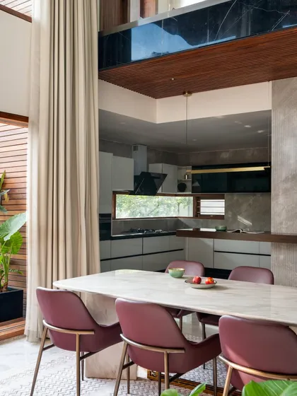 The dining area is visually connected to the kitchen through a long, horizontal window. This design choice maintains a sense of openness while functionally separating the spaces.