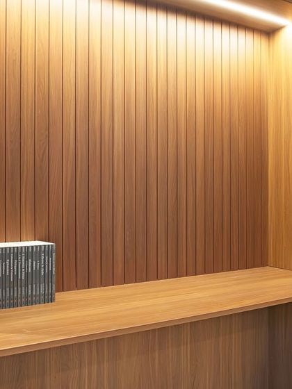 A detail of the fluted wood paneling and integrated desk within the library unit. The texture and warmth of the wood create an inviting atmosphere for work or reading.