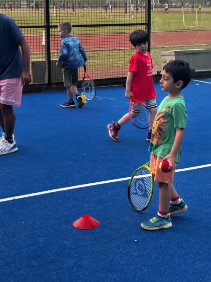 Our coaches are hands on, ensuring every child gets the attention they need. This young player is learning ball control and coordination, key skills that we build upon in our kids' tennis training sessions.