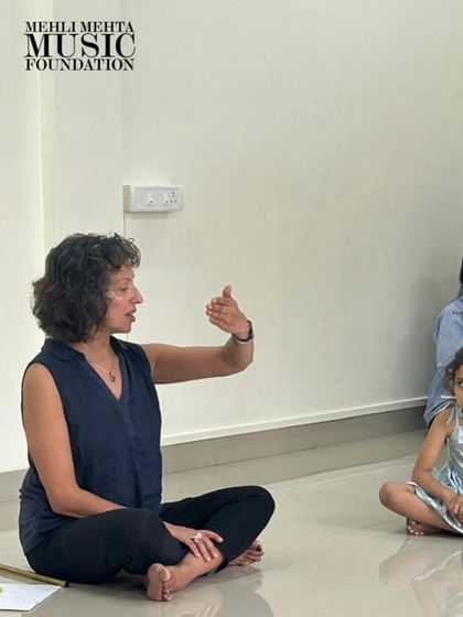 A teacher uses hand signals to guide students in a singing exercise. This technique helps children visualize pitch and dynamics in a simple, intuitive way.