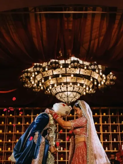 The Varmala moment under a grand chandelier at the Royal Saray. The decor, with its warm lighting and candle wall backdrop, created an intimate yet opulent setting.