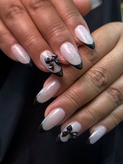 This is a chic and playful take on the French manicure, featuring black tips and adorable 3D sculpted black bows. This is done with long-lasting gum gel extensions.