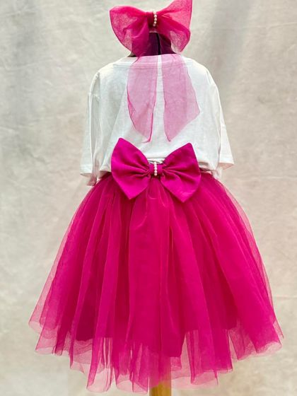 For the girl who loves to have fun. This custom birthday set includes a fuchsia tulle skirt with shorts underneath for easy play, paired with a personalized t-shirt and a matching hair bow.