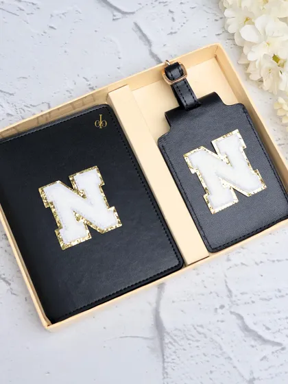 Our classic black passport cover and luggage tag set, personalized with a fuzzy and glittery chenille patch initial. This is one of our most popular travel combos, perfect for adding a touch of personal style to your journeys.