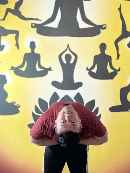 Finding beauty in the basics. A simple standing forward bend in front of a vibrant yoga mural.