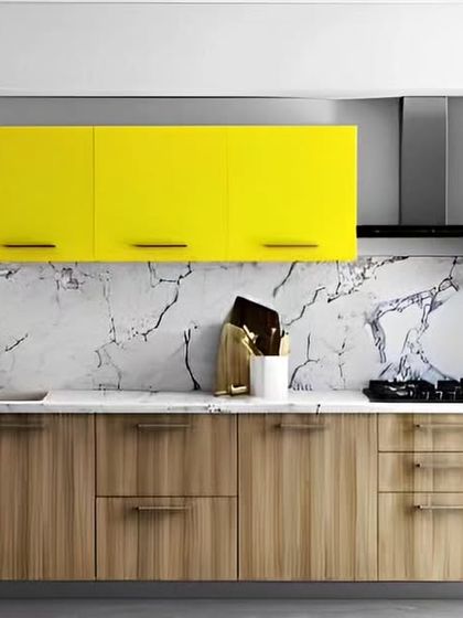 We brought a burst of sunshine into this kitchen with bright yellow overhead cabinets. The vibrant color is balanced by natural wood-finish base cabinets and a white marble-patterned backsplash, creating a cheerful and contemporary look.