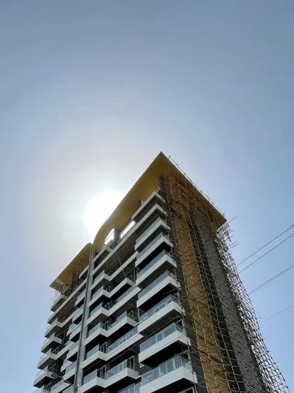 The 'Nanda Hi-Life' tower silhouetted against the sun during construction. This image captures the raw beauty of the structure before the final facade is complete, showing the strong bones of our design.