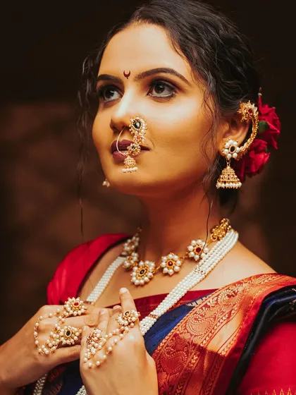 A beautiful portrait capturing the elegance of a model looking upwards, showcasing her intricate Maharashtrian jewelry and the soft texture of her saree.