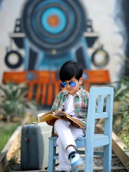 A young boy looking sharp in his sunglasses while reading a book on our train track setup.