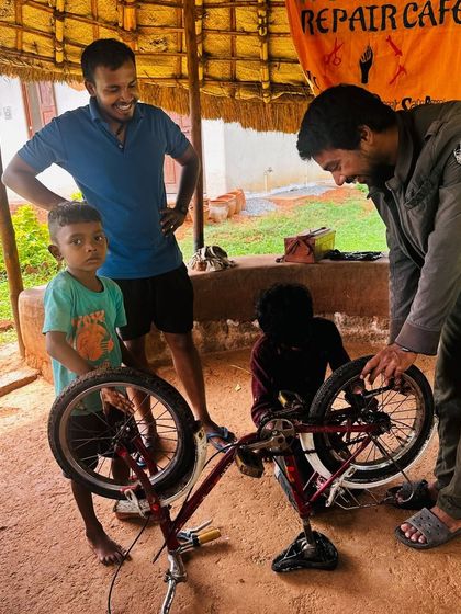 A mentor guides a young boy and his father through a bicycle repair. These moments of shared learning and problem-solving are what our workshops are all about.