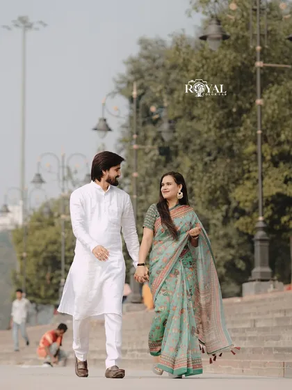 A candid shot of a couple in traditional Indian wear walking hand-in-hand along the promenade by the Ganga.