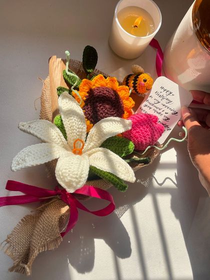 A custom birthday bouquet featuring a sunflower, a lily, and a cute little crochet bee, complete with a handwritten note.