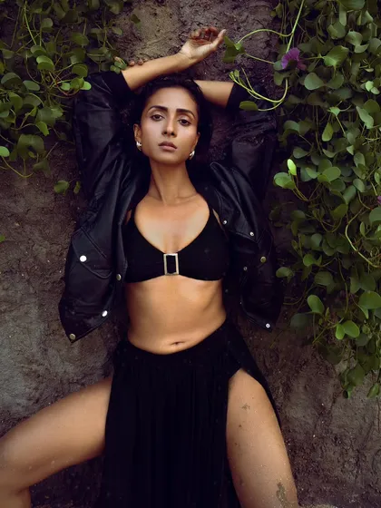 A powerful, wide-legged pose against a rock face covered in vines. This shot combines the rawness of nature with a strong, high-fashion attitude.