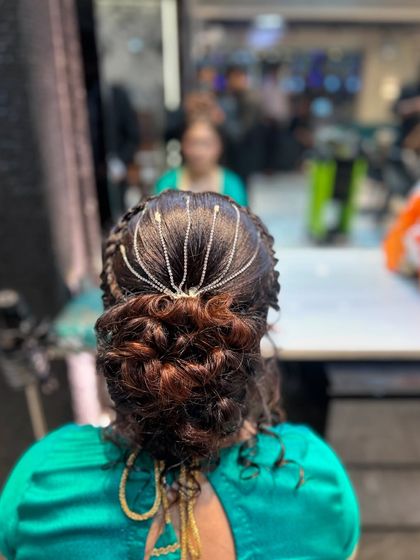 A clear shot of the messy bun with a delicate hair chain, showing the detail of the hairstyle.