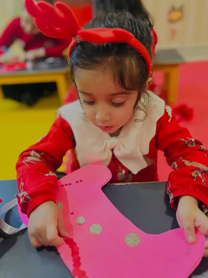 A close-up of a girl concentrating on her pink stocking craft.