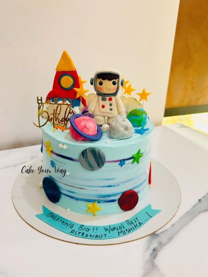 A stellar space-themed cake for an aspiring astronaut, complete with a rocket, planets, and a fondant spaceman.