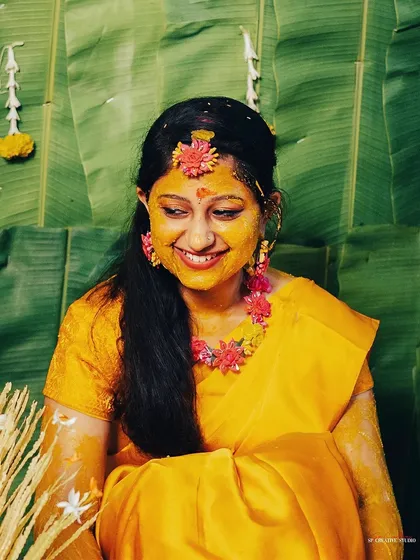 A beautiful portrait of the bride covered in turmeric paste, smiling radiantly. The vibrant yellow and her genuine happiness define the spirit of the Haldi.