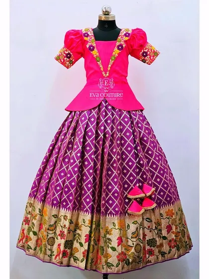 A modern lehenga with a pink peplum top and a purple skirt featuring a Paithani-style floral border.