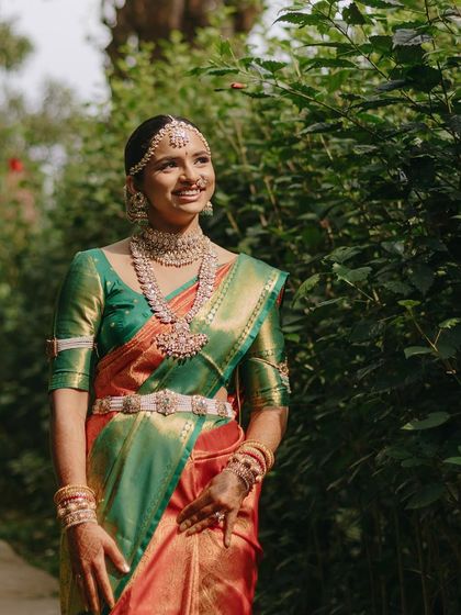 A full-length portrait of the bride in her beautiful silk saree, surrounded by the lush greenery of Coorg.