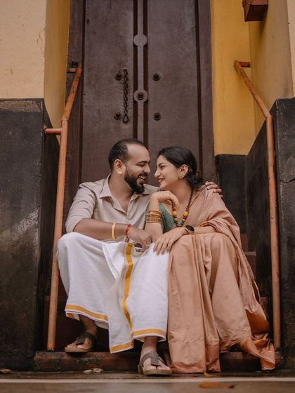 An intimate moment on the steps of a traditional building. The warm tones of their outfits and the setting create a very inviting feel.
