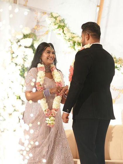 A candid moment captured during a reception. The couple shares a smile against the backdrop of our elegant stage decor, featuring soft lighting and beautiful floral arrangements that create a romantic setting.