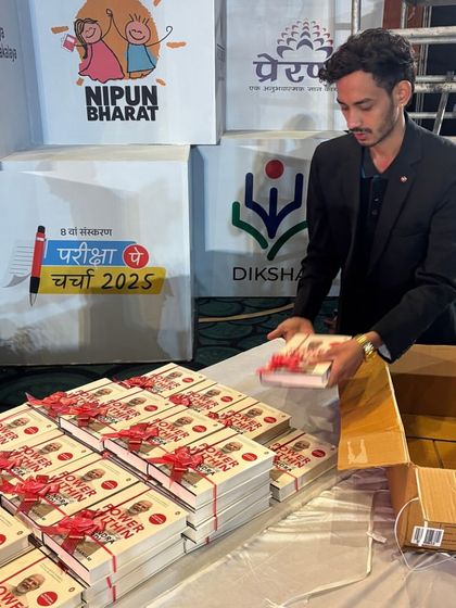 A team member organizing books for distribution at the Akhil Bhartiya Shiksha Sangam. Our role often includes managing materials and logistics.