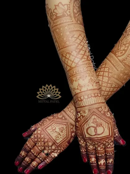 The stunning stain of an engagement mehndi, showing the back of the hands with personalized name and ring motifs.